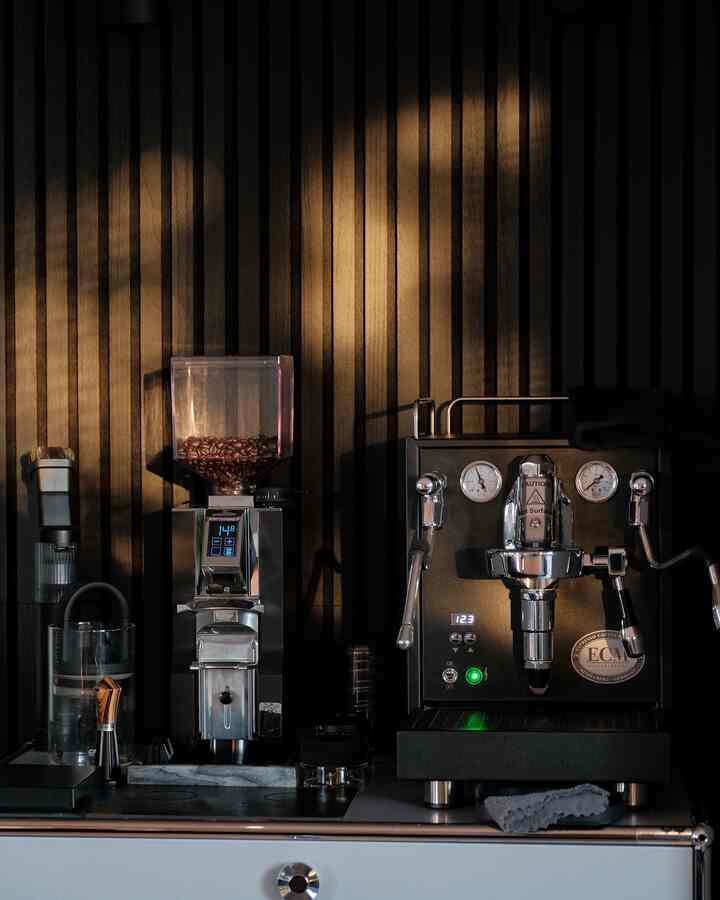 Dark black-toned home cafe space featuring USM cabinet with espresso machine and coffee grinder, creating a sleek interior