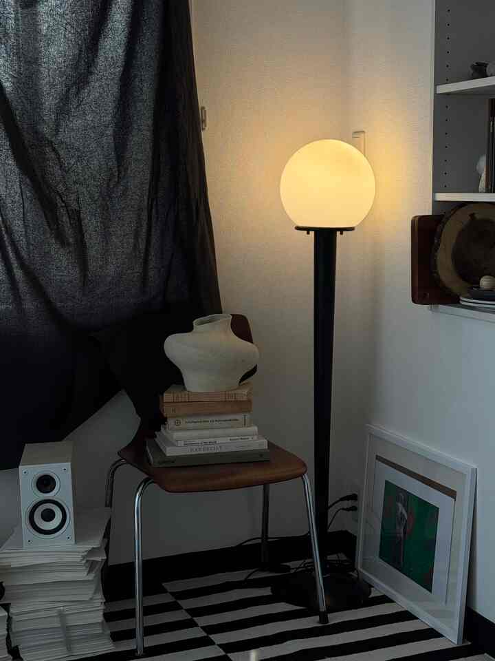 ネイビーのカーテンと茶色の木製チェア、フロアランプが配置されたミッドセンチュリーモダンの空間