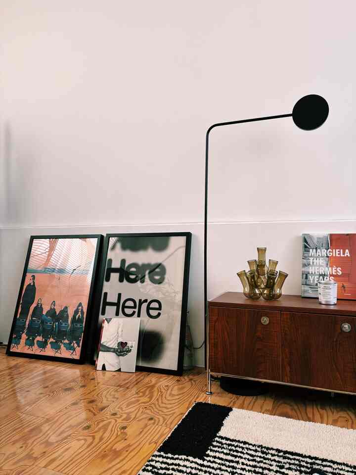 落ち着いたモノトーンと木目調の北欧リビング、ミッドセンチュリーモダンのキャビネットと印象的なポスターが配置されたシンプルなインテリア