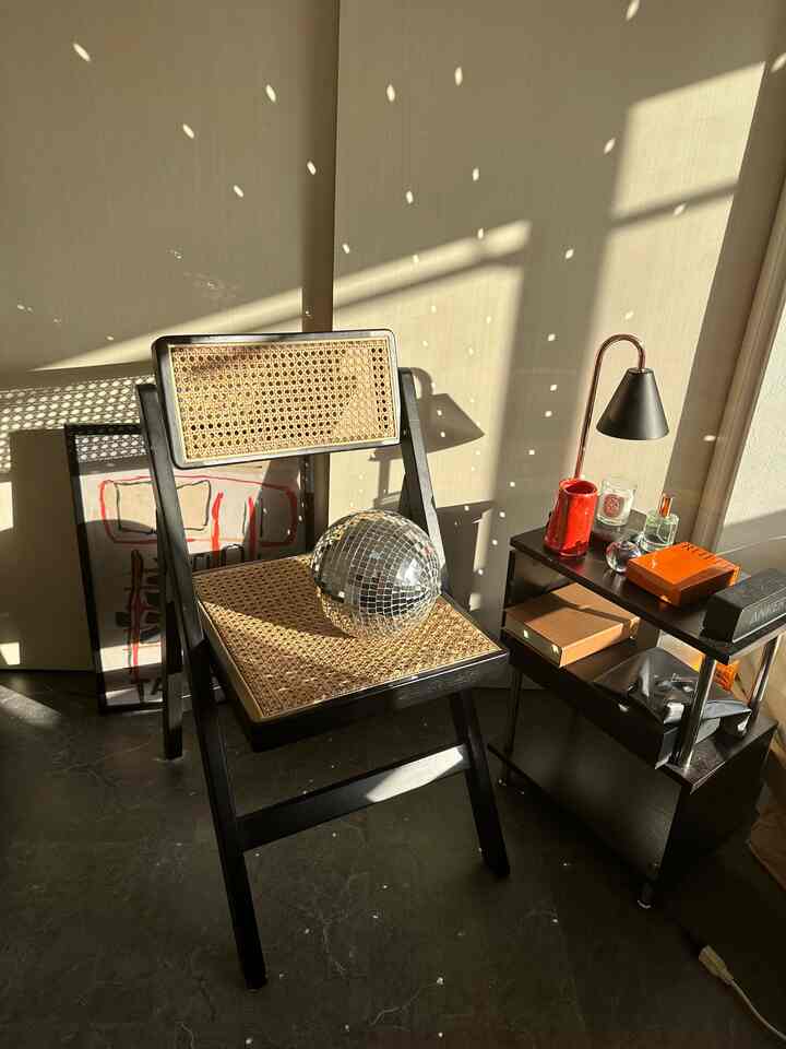 Modern small room with beige walls, black furniture, and a mirror ball reflecting light spots