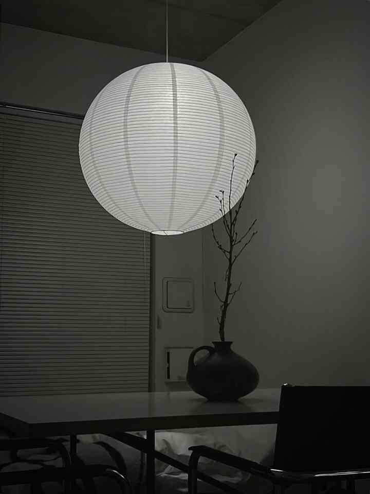 白を基調としたダイニングルーム、中央に大きなペンダントライトと花瓶が配置されたモダンでシンプルなインテリア