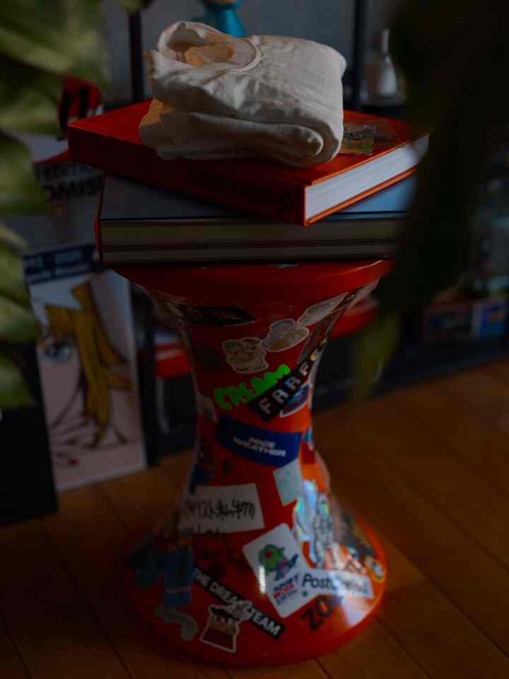 赤いステッカーが貼られたスツールと木目調の床が見える一人暮らしの1LDK空間