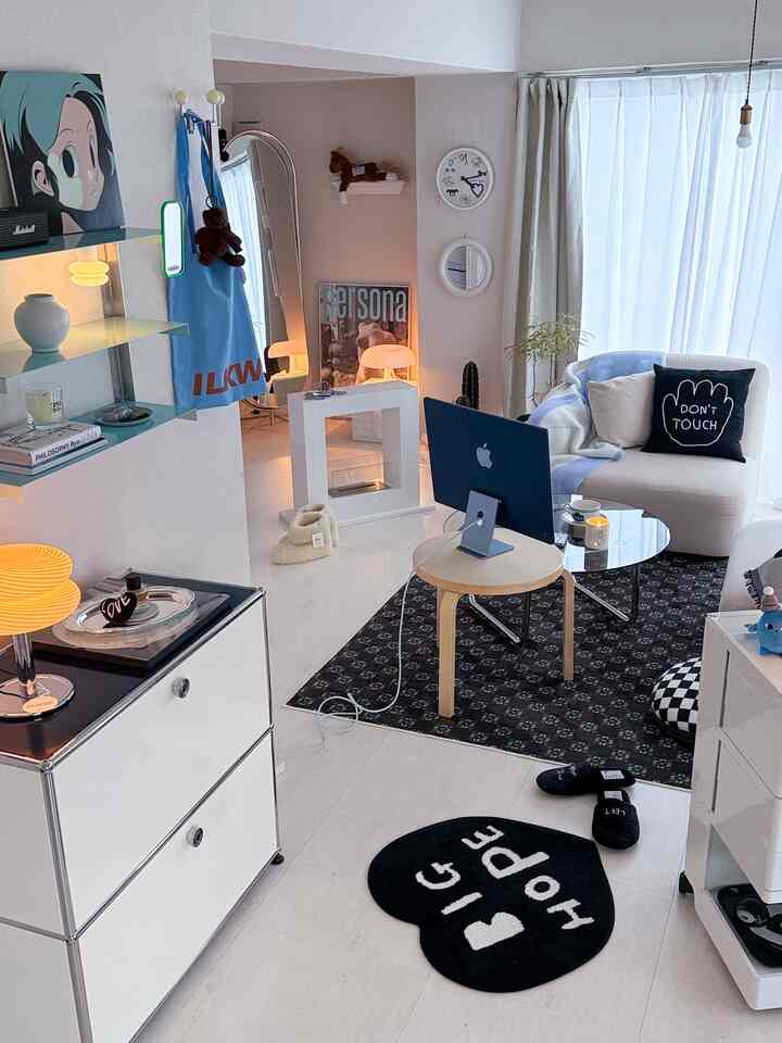 白と黒の色調のリビング、ソファとラグ、デスク上のiMacが配置されたモダンでナチュラルな雰囲気のインテリア