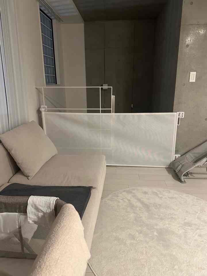 ベージュのソファと白い安全フェンスが配置されたナチュラルな雰囲気のリビング