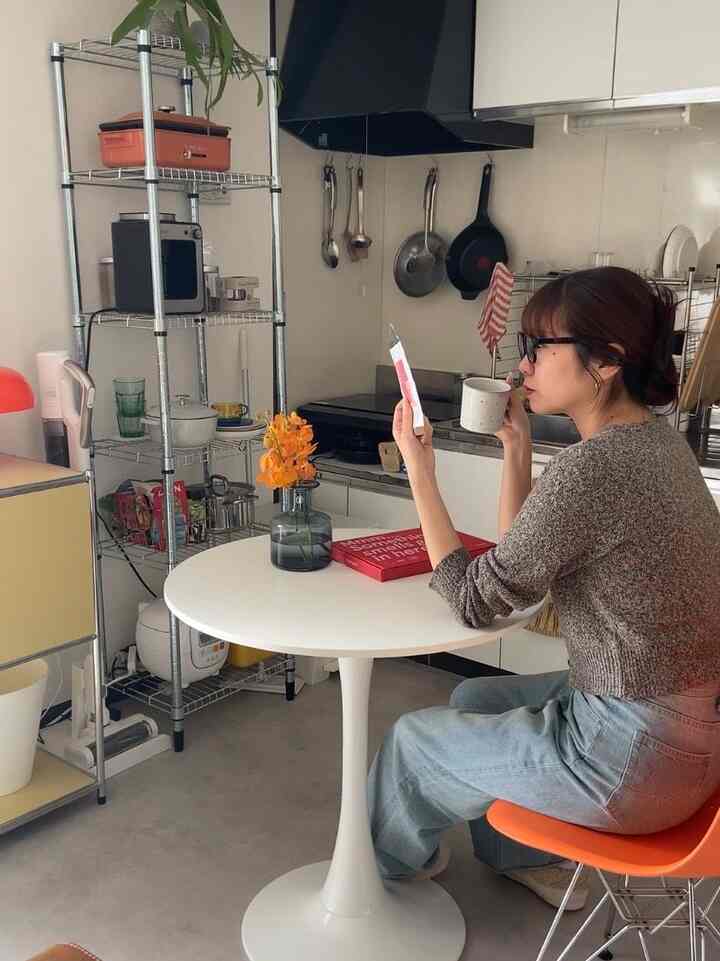 白とオレンジの色調の一人暮らし用キッチンダイニング、ミッドセンチュリーモダンスタイルのシンプルで居心地の良い空間