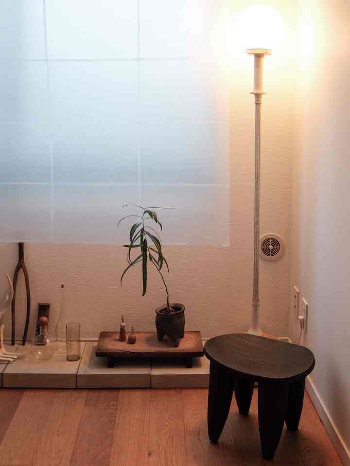 ブラウンの木目調の床とスツール、フロアランプが配置されたナチュラルなリビングのコーナーインテリア