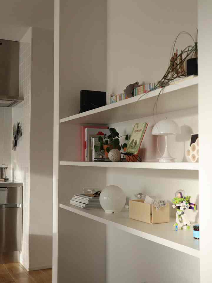 白を基調としたミッドセンチュリーモダンスタイルのキッチンと棚が配置されたインテリア