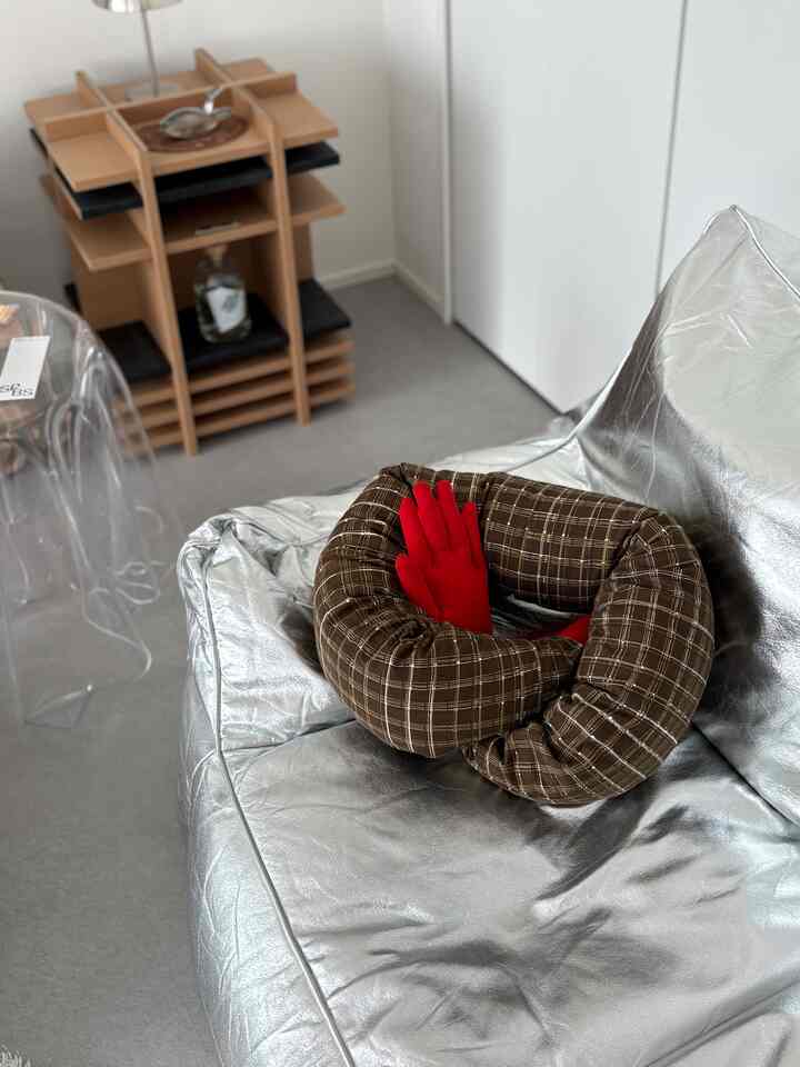 Silver-toned compact space featuring a central metallic bean bag sofa with red gloves, showcasing a minimalistic interior