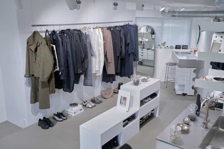 グレーと白のモノトーンのクローゼット空間、整然とした服と靴が配置されたミニマルなインテリア