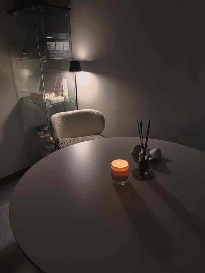 白を基調としたダイニング、丸いダイニングテーブルと柔らかいアームチェアが配置され、キャンドルとディフューザーで温かみのある雰囲気のあるインテリア