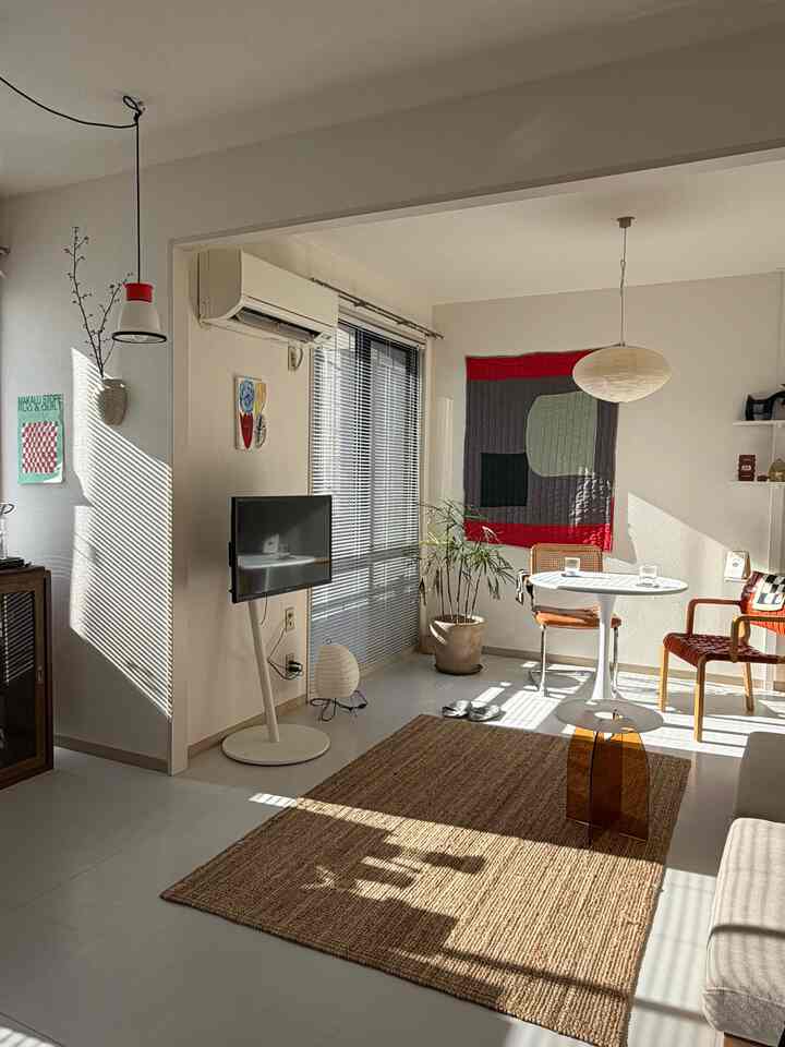 ナチュラルトーンのリビングとダイニングスペース、丸いダイニングテーブルとラタンスツールが配置された明るく居心地の良いインテリア