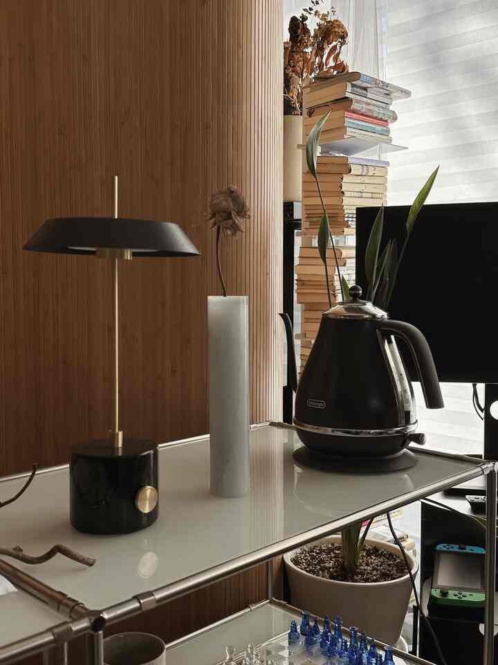 ナチュラルモダンなインテリア、メタルシェルフに置かれた黒い電気ケトルと積まれた本、植物が配置された印象的な空間