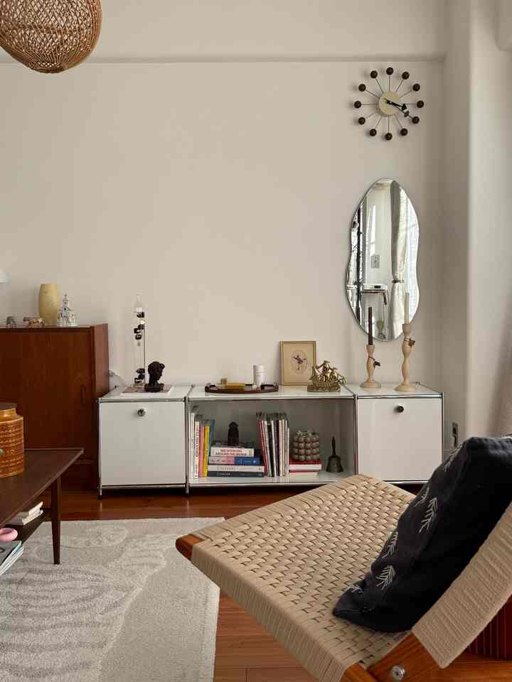 Modern natural living room in white and brown tones featuring modular storage and a woven chair