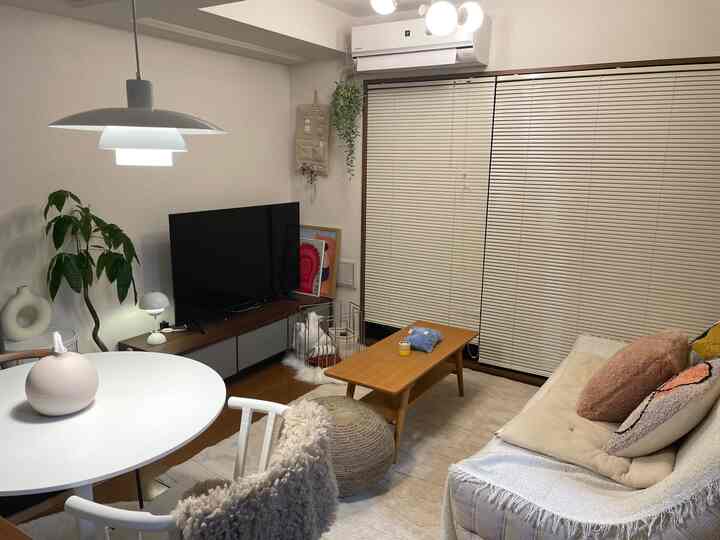 Bright white and brown wood tones in a studio apartment living room featuring minimalist Mid-Century Modern furniture and warm lighting for a cozy atmosphere