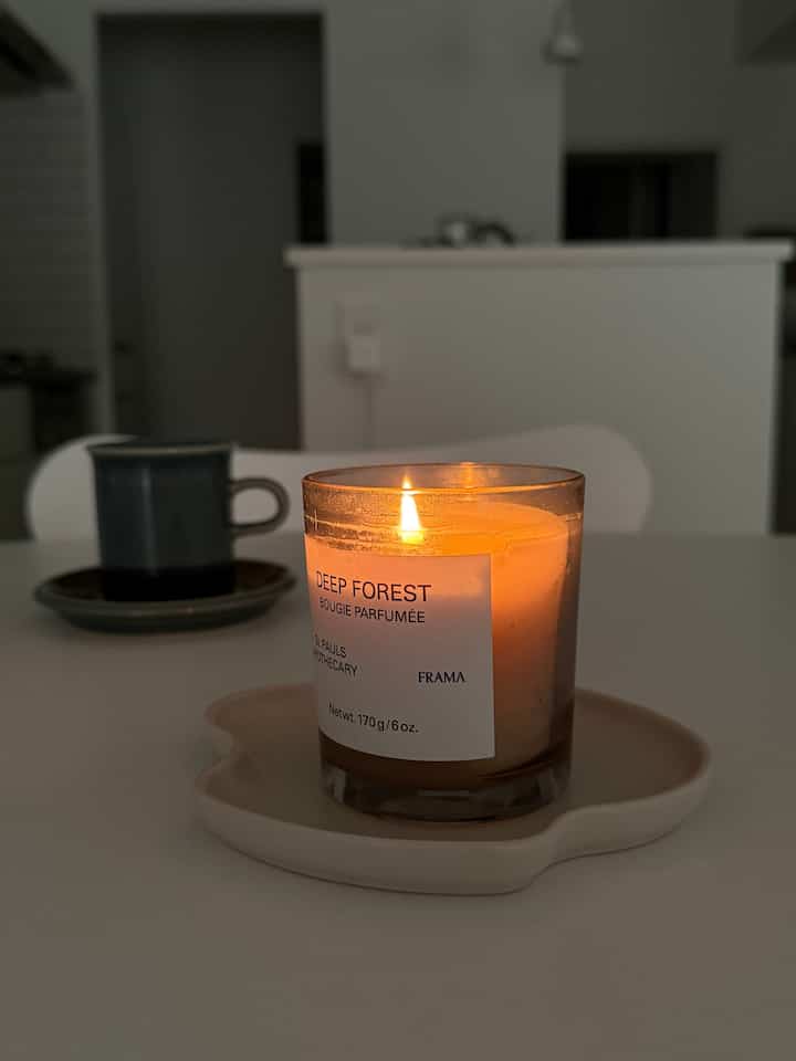 White-toned kitchen table featuring a lit candle and cup, creating a minimal Nordic atmosphere