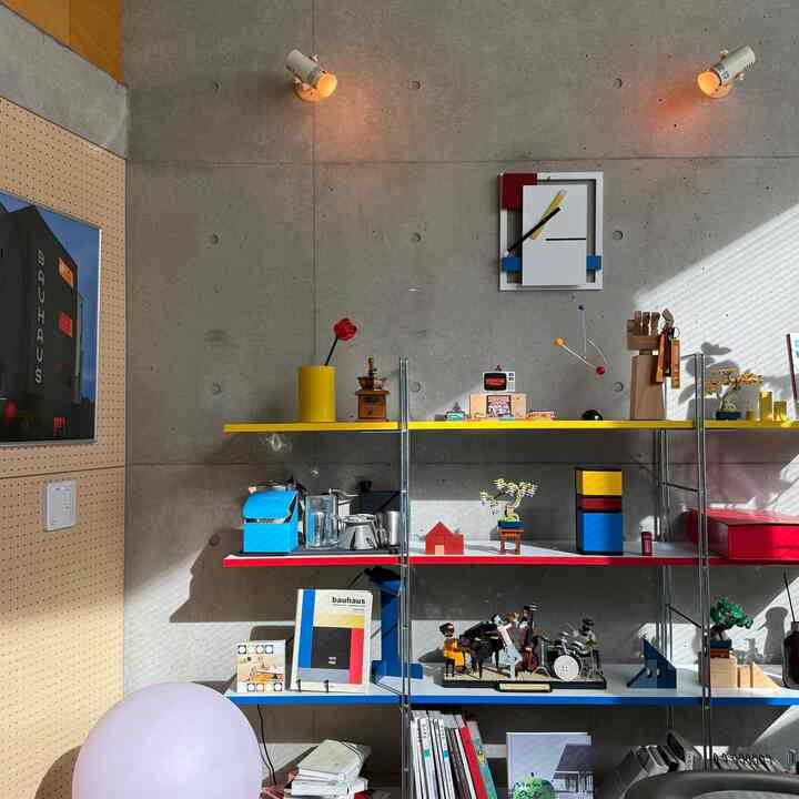 Industrial-style storage space with exposed concrete wall and colorful primary-toned open shelving showcasing Bauhaus design elements