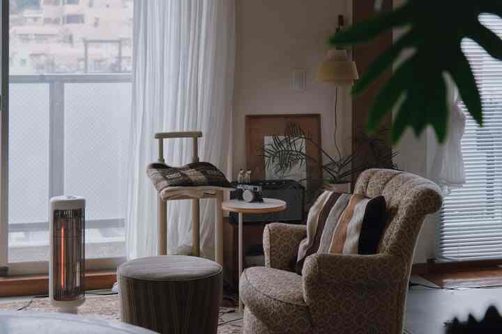Natural color toned living room featuring vintage armchair, side table, curtains creating cozy atmosphere
