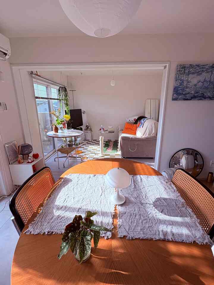 ナチュラルカラーのミッドセンチュリーモダン空間、木製のダイニングテーブルとテーブルランプ、壁に掛けられたモネの絵がある印象的なインテリア