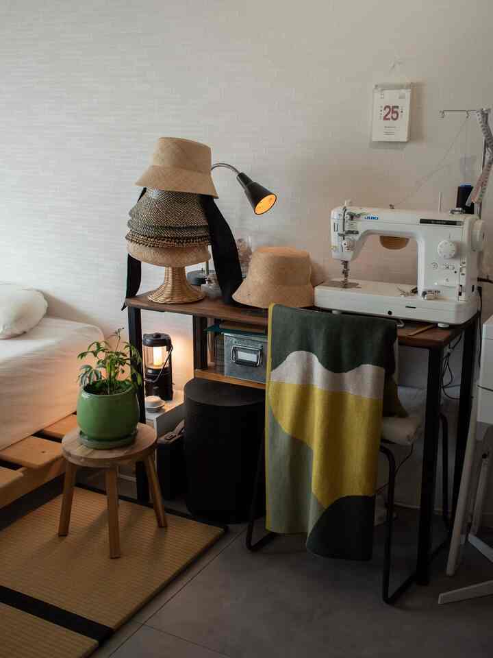 Beige-toned studio workspace featuring sewing machine and hat-design desk with cozy, functional atmosphere