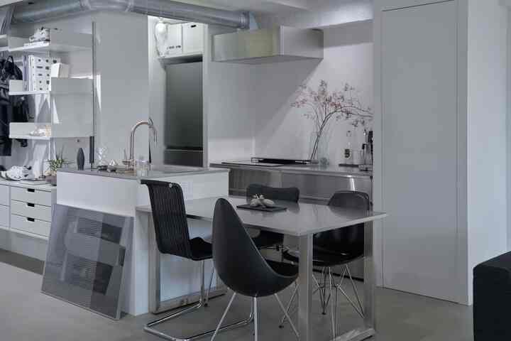 Gray and stainless-toned kitchen space featuring modern dining table and chairs with a clean, sleek interior