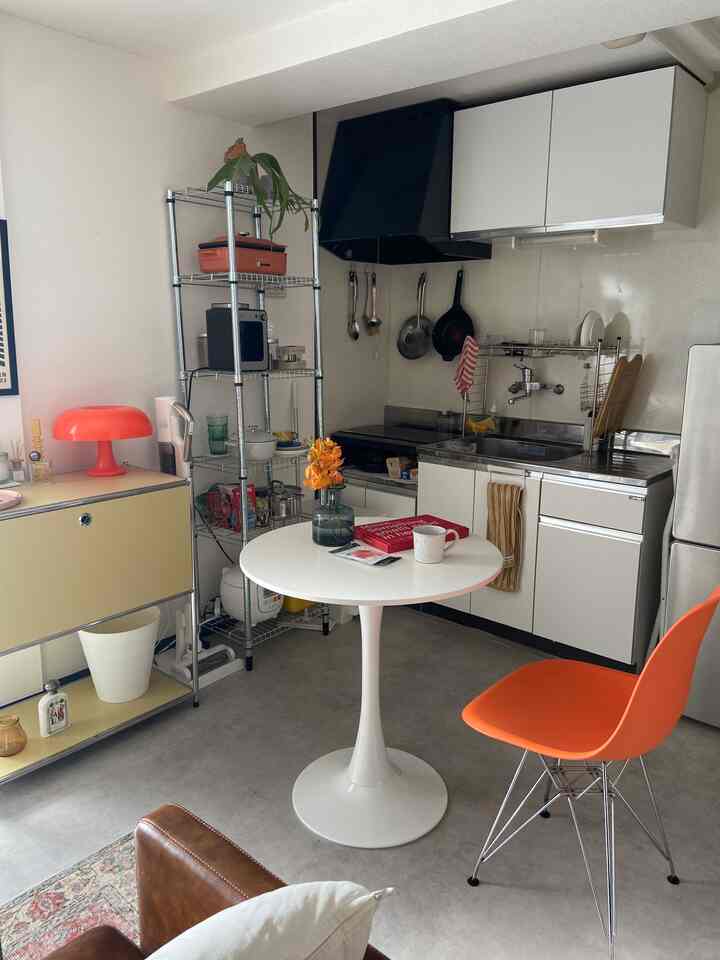 ホワイトとオレンジのトーンが調和した一人暮らし向けの1DKキッチン＆リビング、ミッドセンチュリーモダン家具が配置されたコンパクトな空間