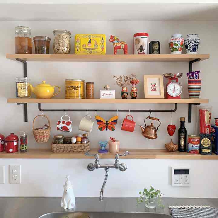 ナチュラルな色調のキッチンの壁、木製の棚に様々なオブジェが並ぶ雰囲気のあるインテリア