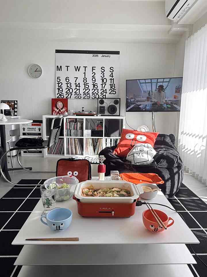 白を基調としたミニマルなリビングで、中央にローテーブルとビーズクッション、モノトーンのラグが配置された雰囲気ある空間