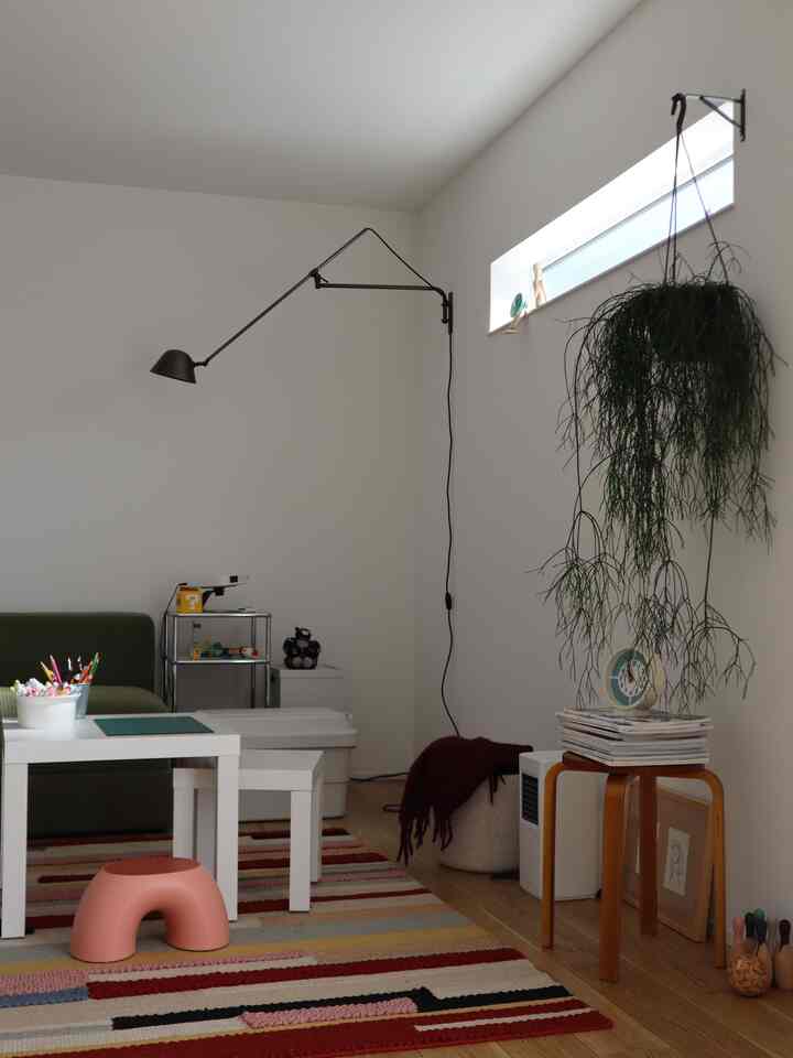 A Nordic-style kids' room with white walls and wood tone flooring, colorful rug and child furniture creating a cozy atmosphere