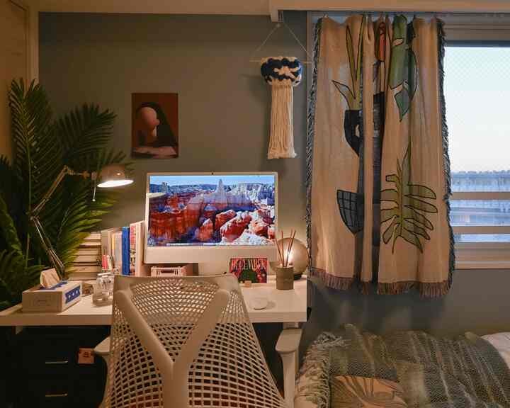 暖かいナチュラルトーンの寝室兼ホームオフィス空間、白いデスクとHerman Millerのオフィスチェアが配置された居心地の良い在宅勤務環境