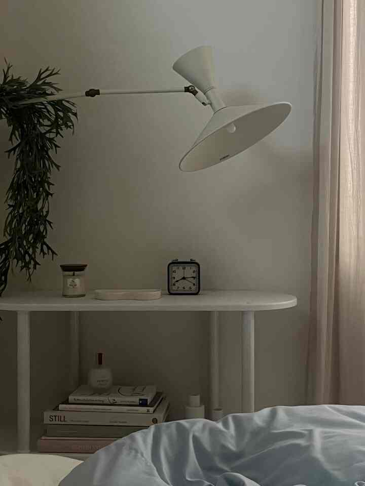 ベージュのカーテンと青い寝具が調和したシンプルな寝室、温かみのある自然光とミニマルな家具配置が印象的な空間