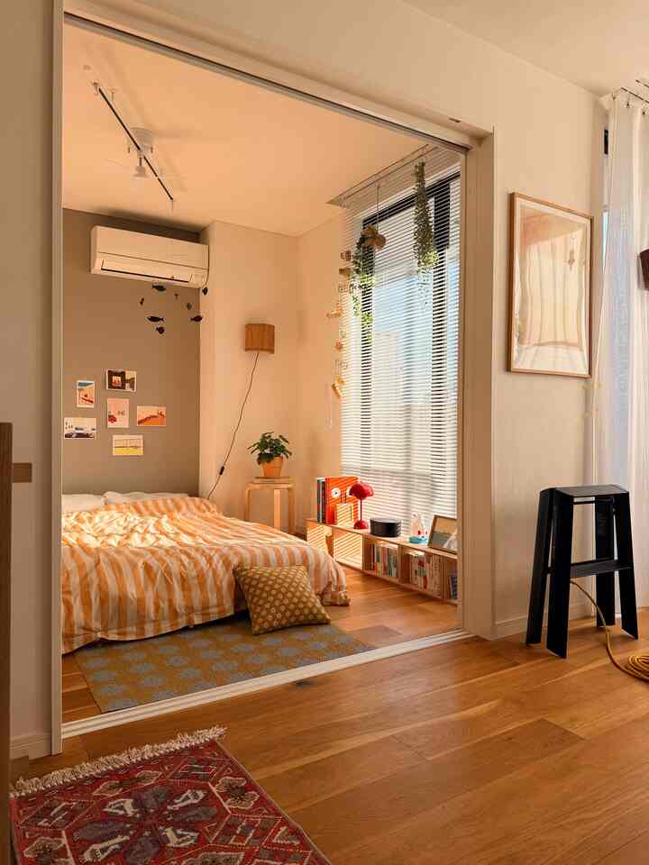 ベージュとオレンジの色調が特徴の寝室、ナチュラルモダンな寝具と木製の床が調和した雰囲気のあるインテリア