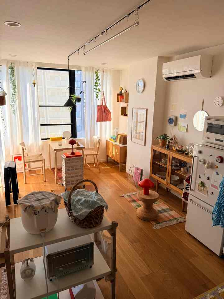Natural wood tones and white dominate this compact two-person kitchen-living room space with simple, functional furniture
