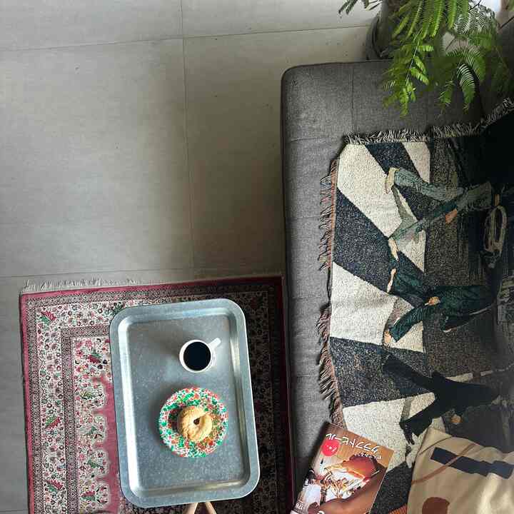 グレーのソファとビンテージ風の赤いペルシャ絨毯、ビートルズ柄のスローとコーヒーがある温かみのあるリビングスペース