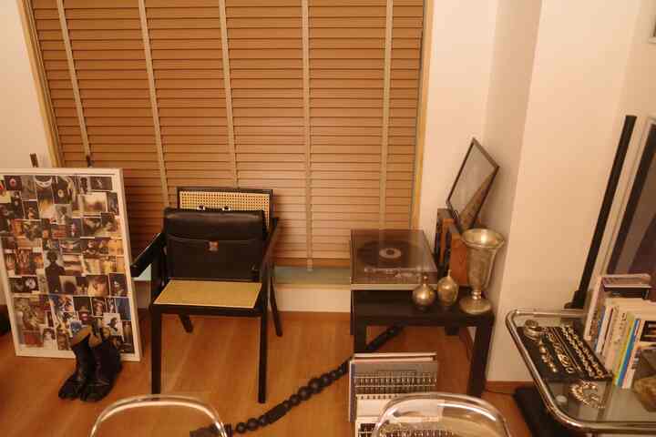 ブラウン調の1LDKリビング、ブラックチェアとサイドテーブルにターンテーブルと額縁が配置された落ち着いた空間