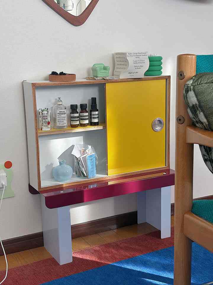 鮮やかな黄色と赤色が印象的な、小さな部屋に置かれた収納棚のある韓国風インテリア