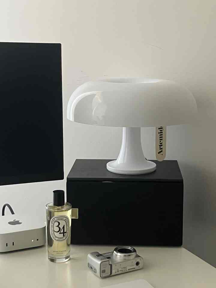 白と黒のモノトーンのホームオフィスデスクにArtemideのテーブルランプ、モニター、ディフューザーが配置されたシンプルな空間