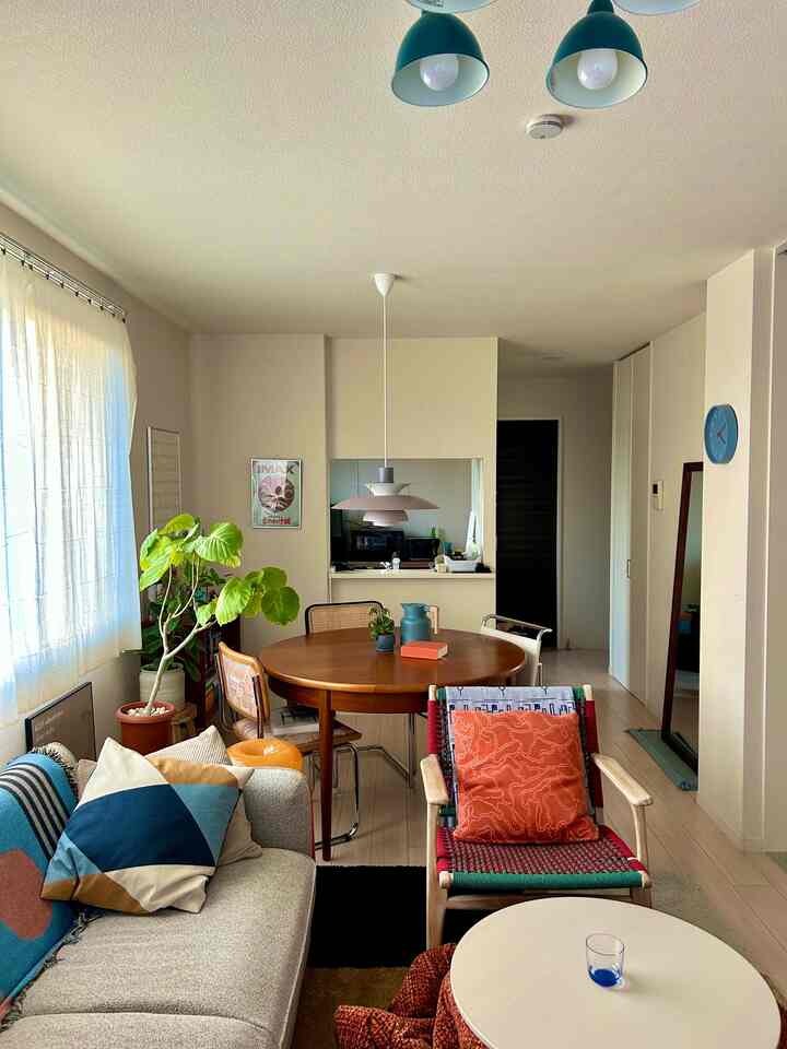 A natural wood tone and light gray sofa combine in a mid-century modern living and dining room space
