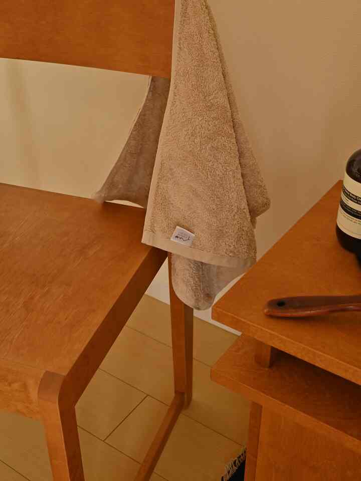 ナチュラルな色調のバスルーム、温かみのあるブラウンの木製家具と柔らかいベージュのタオルが調和した雰囲気のあるインテリア