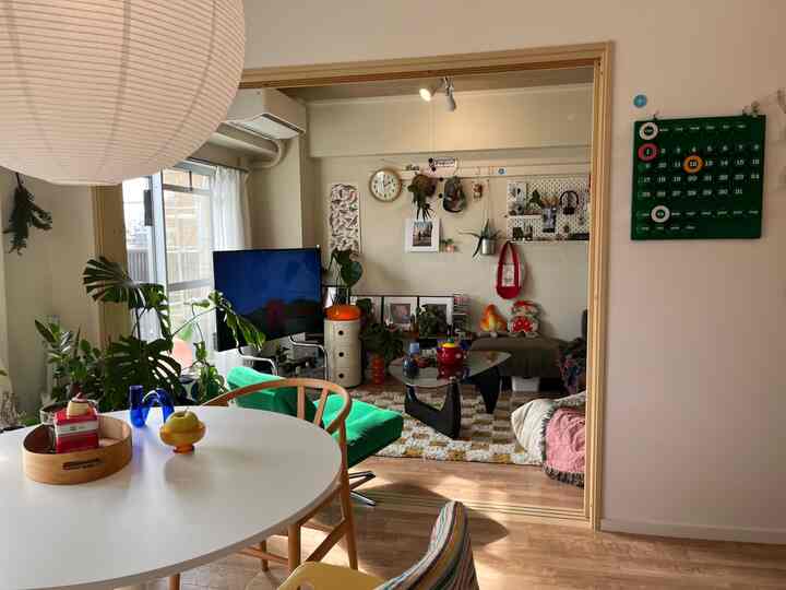 White and wood-toned dining and living room featuring a round table, green chair, plants, and cozy atmosphere