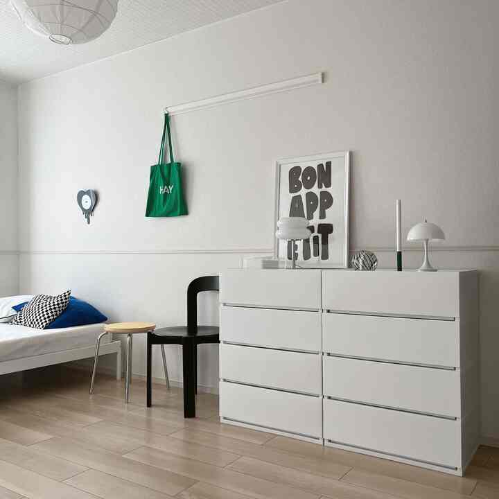 White and black toned bedroom featuring a mid-century modern dresser and chair with a simple, clean interior