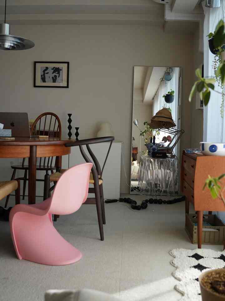 ブラウンの木目調とピンクの椅子が調和した6畳のダイニングルーム、鏡とカーテンが配置されたモダンで居心地の良い空間