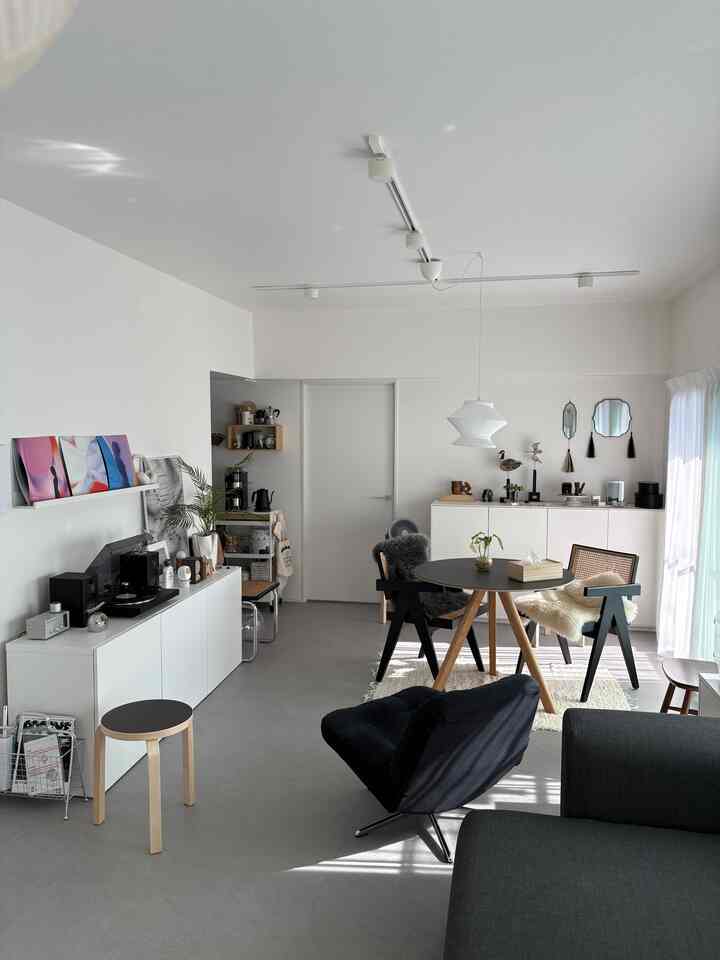 Modern dining room in white and black tones, featuring a round dining table and chairs arranged in a clean, airy space