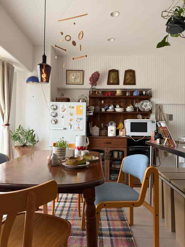 白と木目調のキッチンとダイニング、エジソン電球の照明とラグが調和したナチュラルな空間