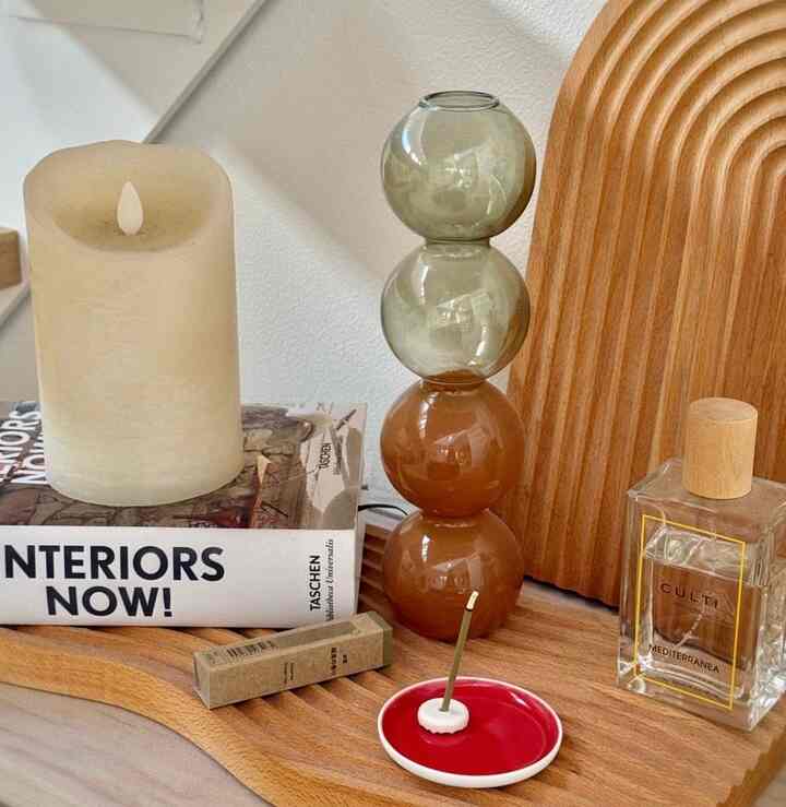 ナチュラルな木目調トレイにベージュのキャンドル、茶色の球体オブジェ、無印良品のお香製品が配置されたシンプルモダンなインテリア空間