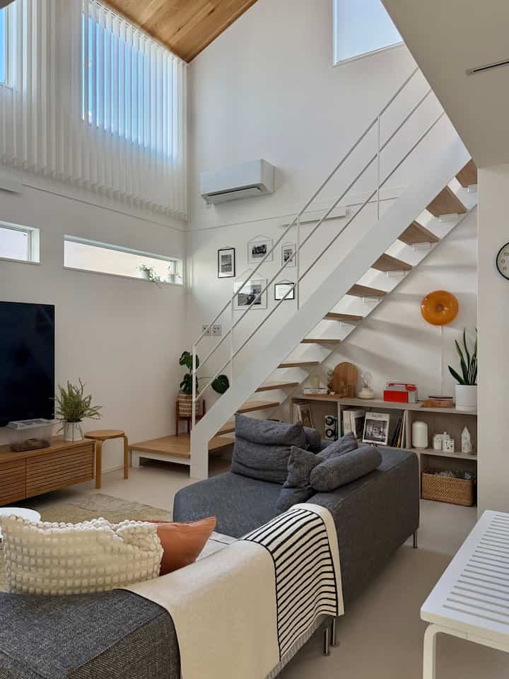 White and wood tone loft living room featuring modern sofa and picture frames with a stylish atmosphere