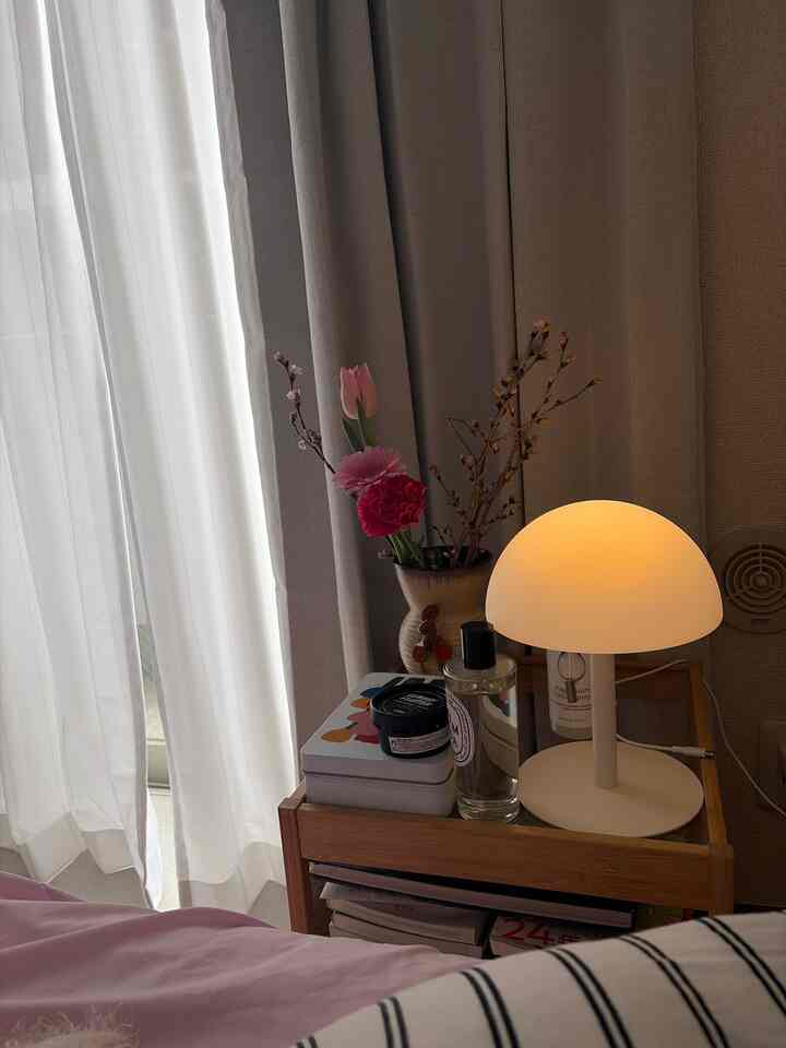 ブラウンの家具とベージュのカーテン、柔らかい光のテーブルランプが配置された寝室の印象的な空間