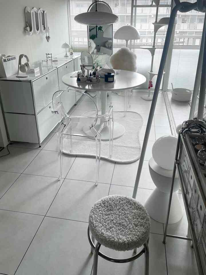 Compact studio living room in white and transparent tones featuring a Louis Ghost armchair, round dining table, and a cat tower with a clean aesthetic