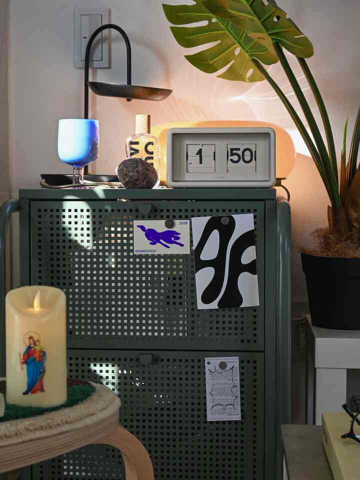 グリーンのチェストとレトロな卓上時計、ムード照明があるナチュラルトーンの寝室インテリア