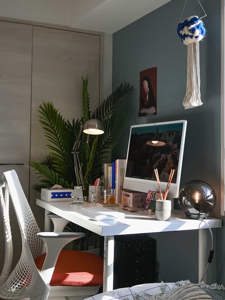 Bright white and green toned home office featuring a white desk, office chair, books, and computer in a modern workspace