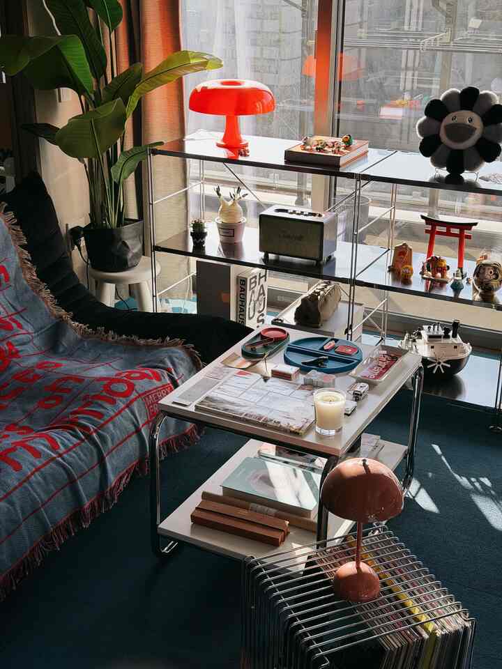 レッドとブラックのトーンが印象的な居心地の良いリビング、モダンなソファとテーブル、植物やヴィンテージの小物が配置されたインテリア